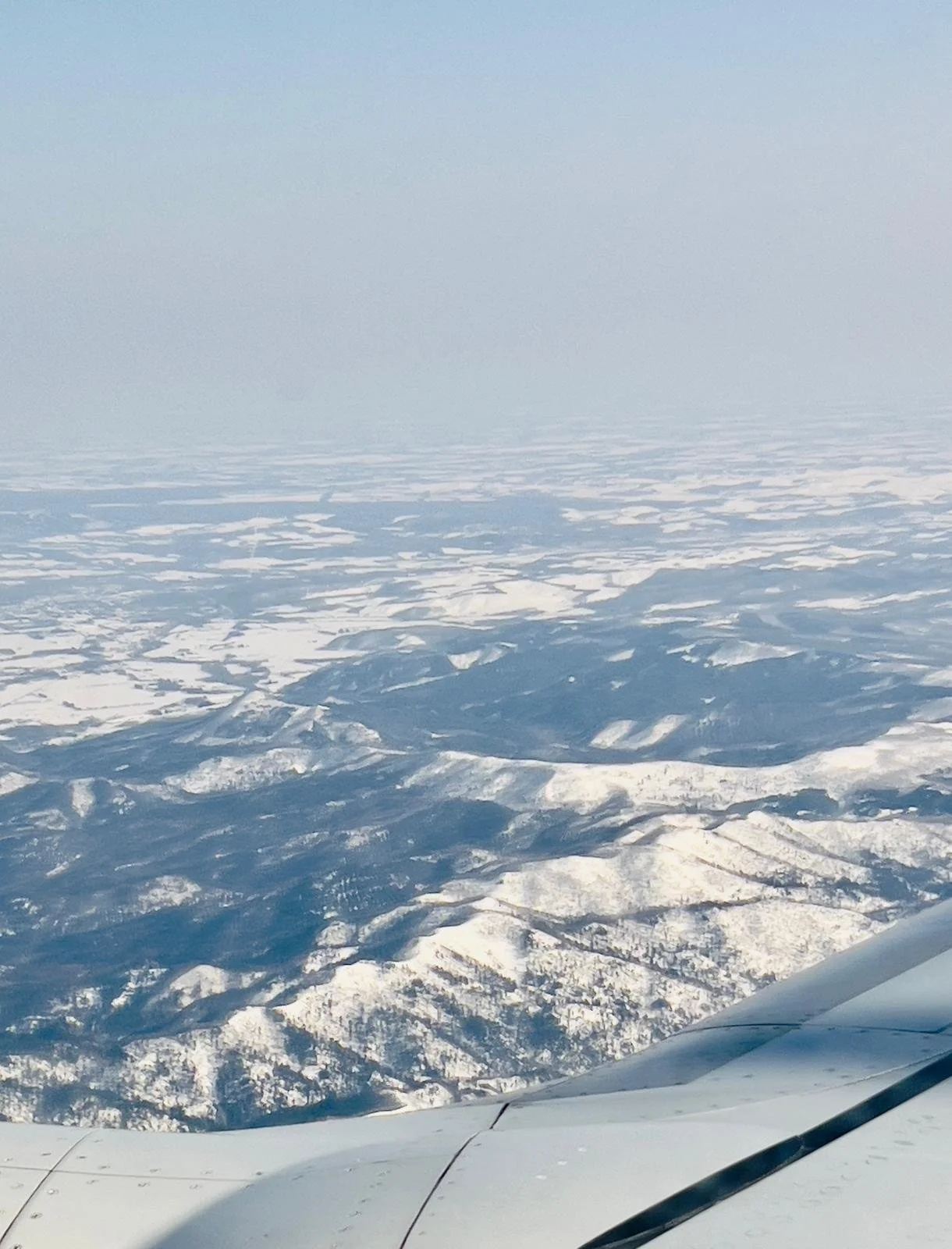 Vue depuis le hublot au-dessus de l’aile sur les montagnes enneigées de Hokkaido