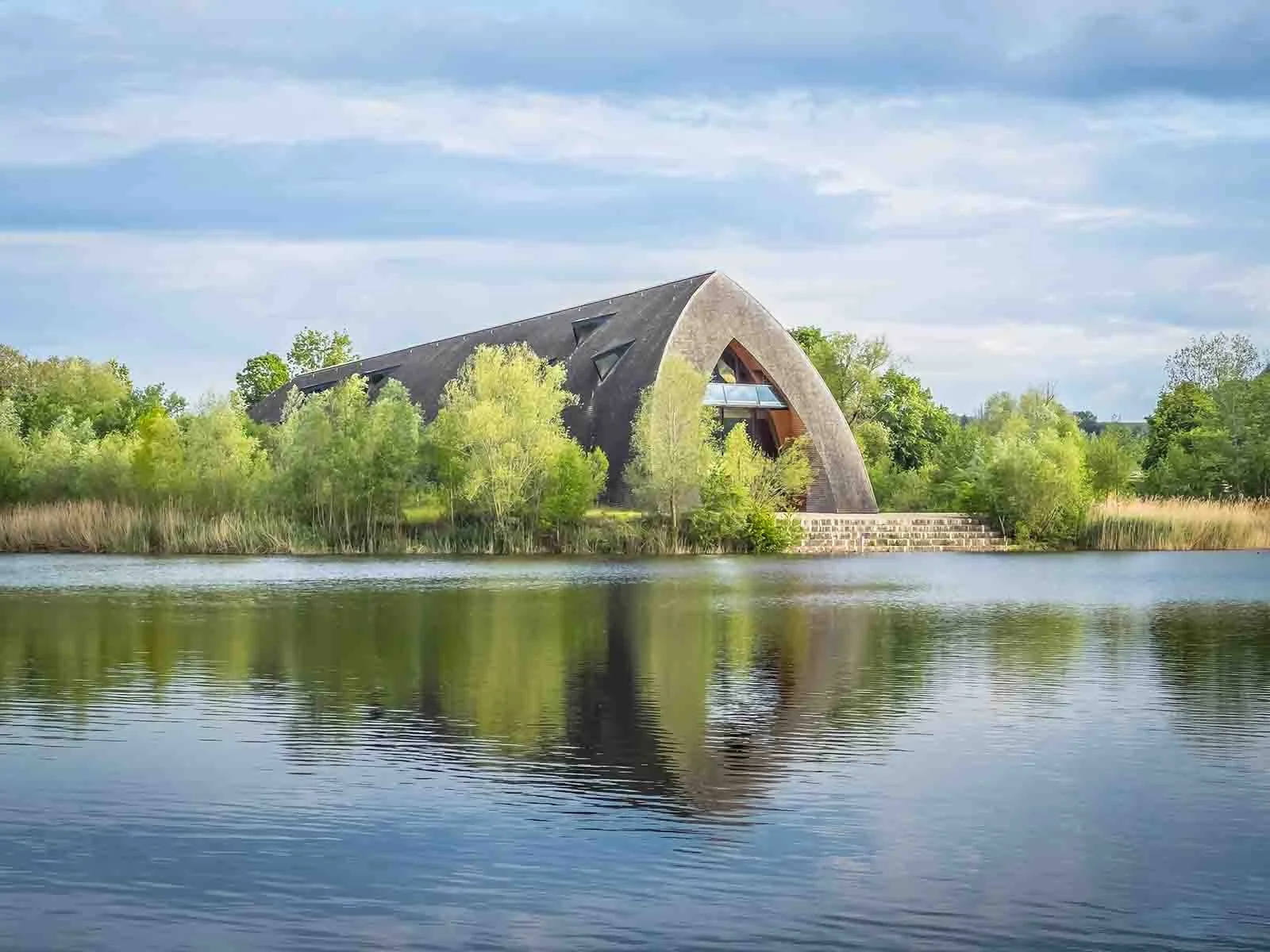 Il Biodiversum di Remerschen con il tetto ad arco si riflette nel lago, Lussemburgo