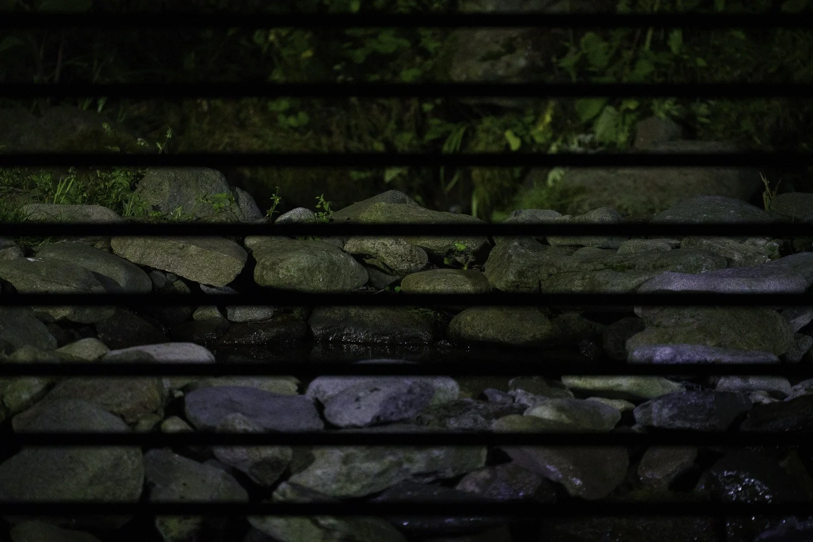 Night stream bed with stones and regular dark horizontal stripes as an example of banding from artificial light.