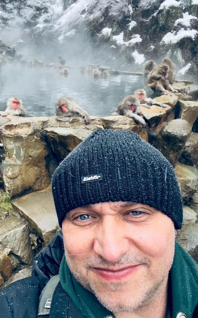 Markus in front of a group of Japanese macaques bathing in a steaming hot spring in Japan.
