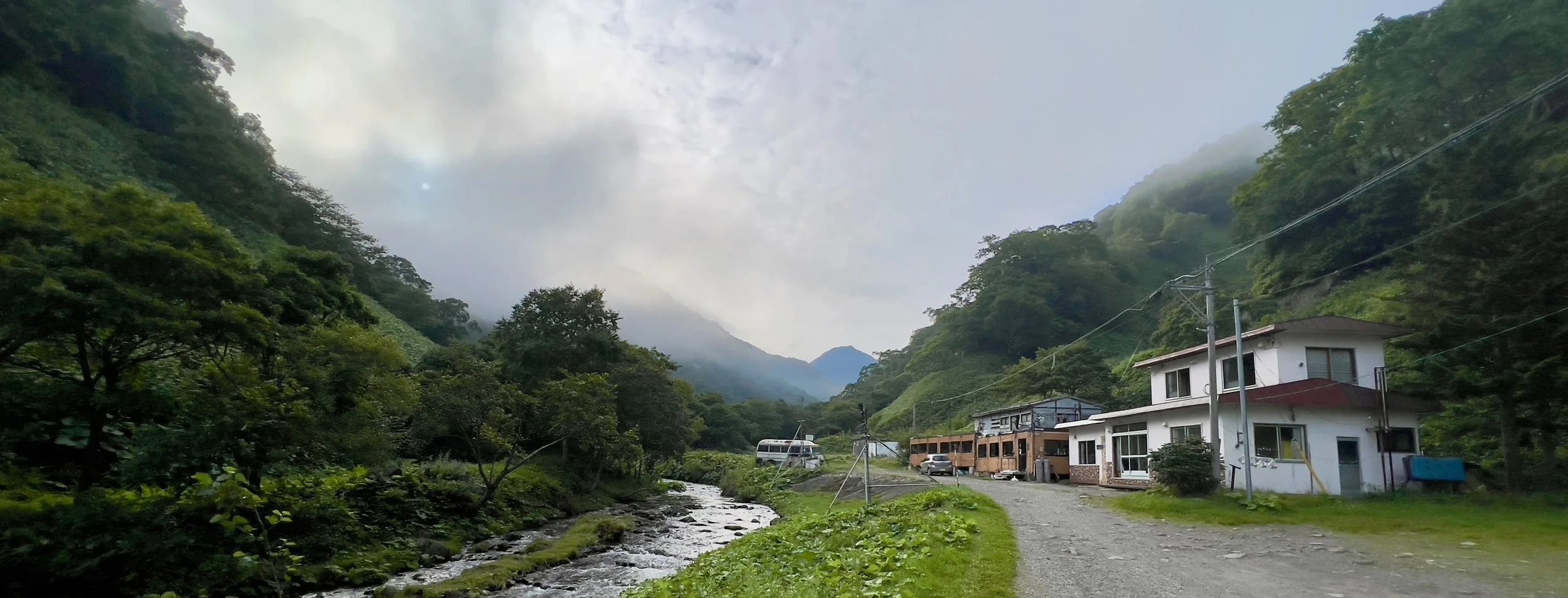 Small guesthouse by a river in the misty forested Shiretoko valley, Hokkaido.