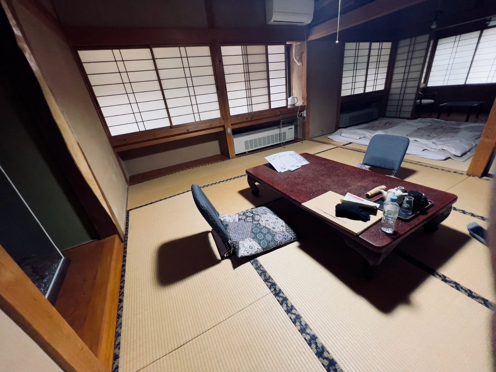 Traditional tatami room in a Japanese ryokan with a low table and made-up futon bed.