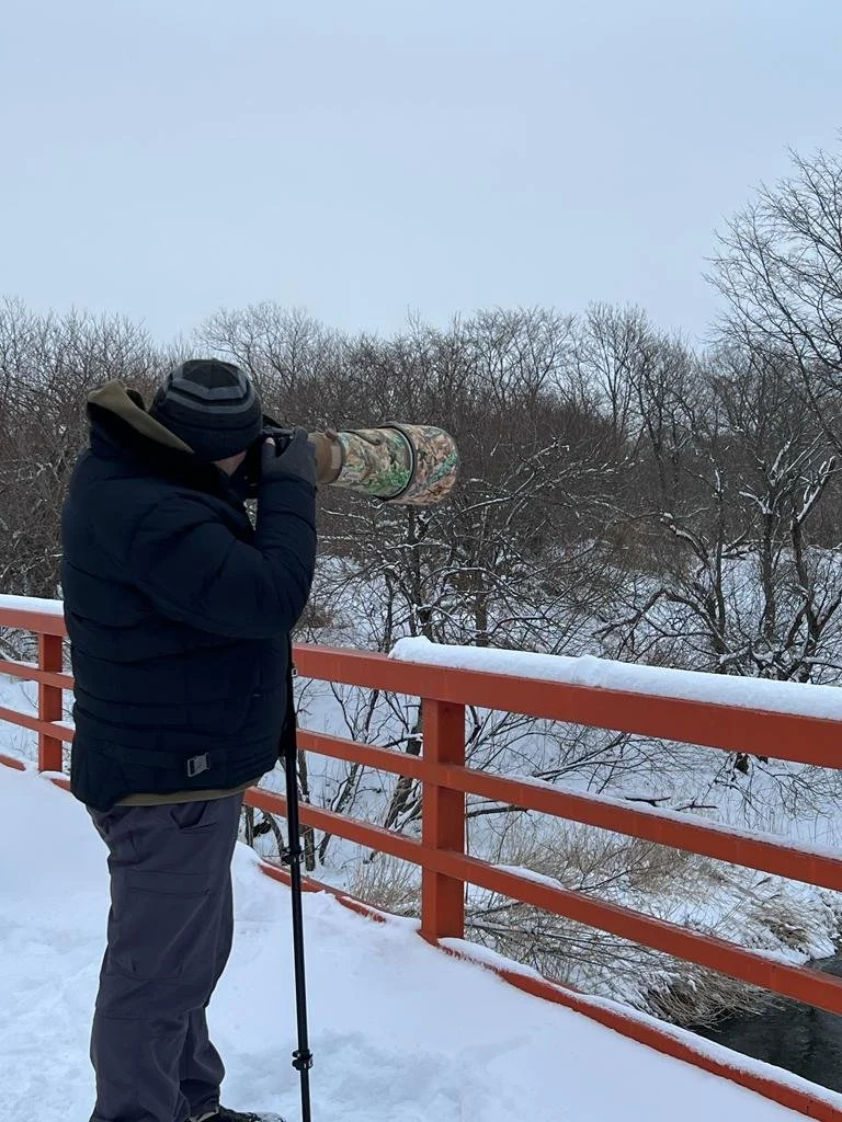 Markus Nilles photographiant depuis un pont dans un paysage d’hiver enneigé, au Japon.